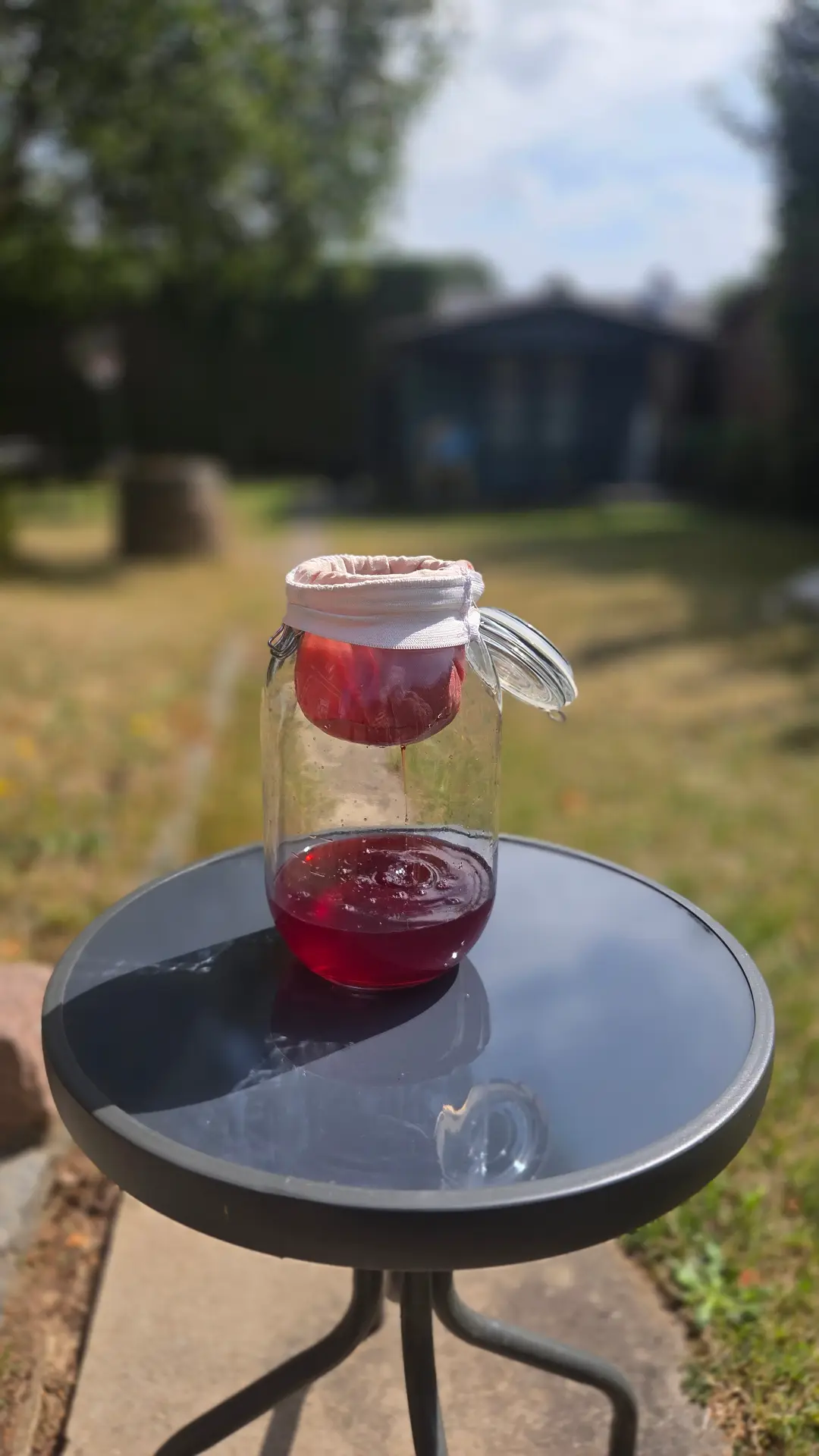 Filtration artisanale du fruit dans un bocal, au soleil du jardin